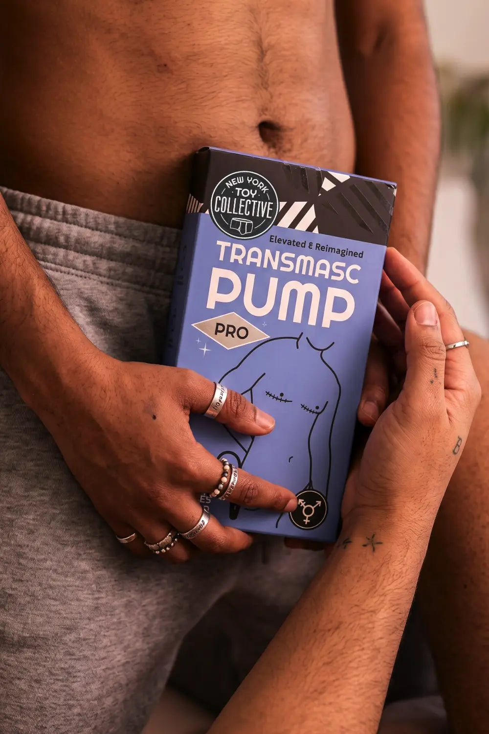 Person holding a 'Transmasc Pump Pro' product packaging