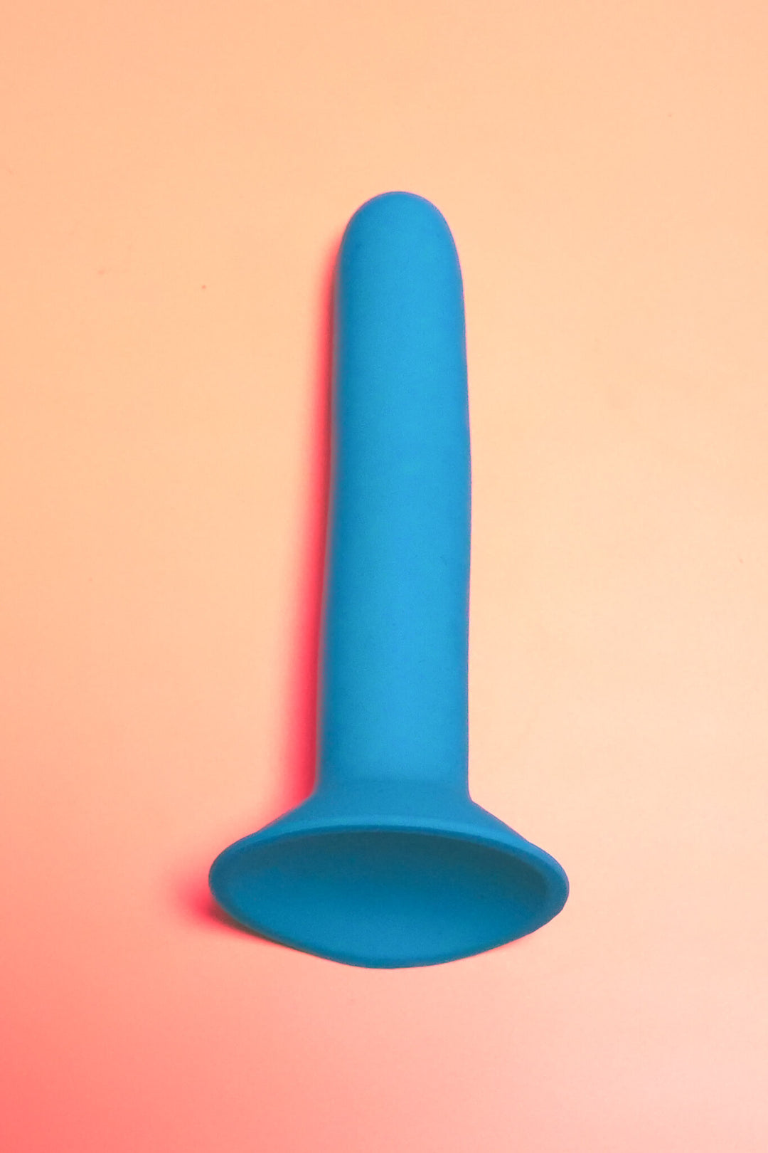 Blue silicone product on a gradient pink and orange background