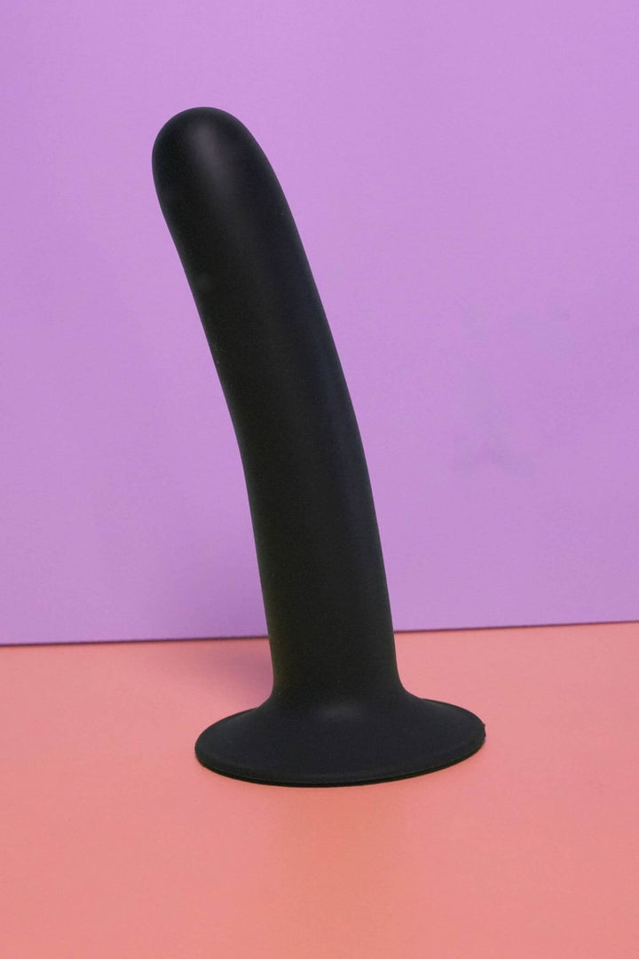 Black silicone toy on a gradient purple to pink background