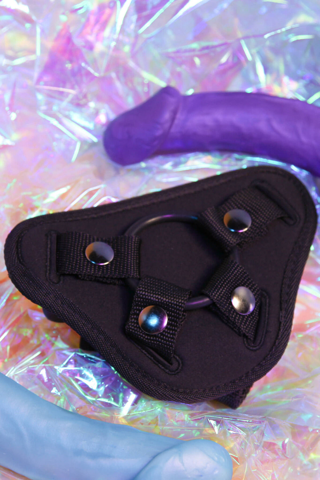 Black triangular holster with metallic studs on a colorful, reflective background